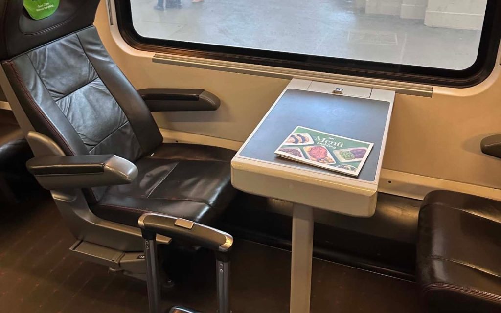 Train seat with luggage and travel reading for planning a Budapest journey
